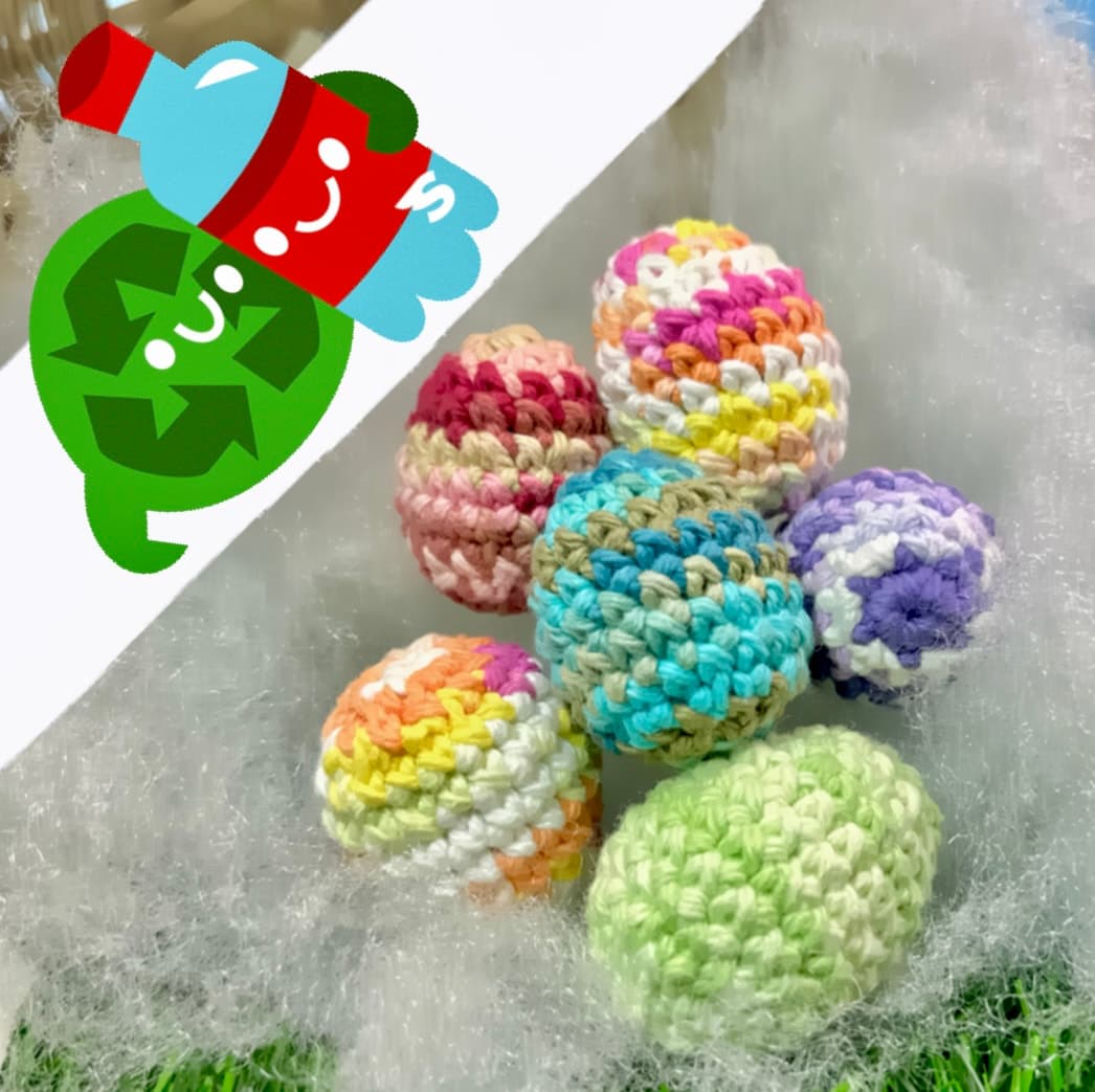 Six small crocheted eggs in pastel colors with white variegated stripes arranged on a gray surface. Each egg features a unique color pattern including pink, rainbow, turquoise, purple, and lime green.