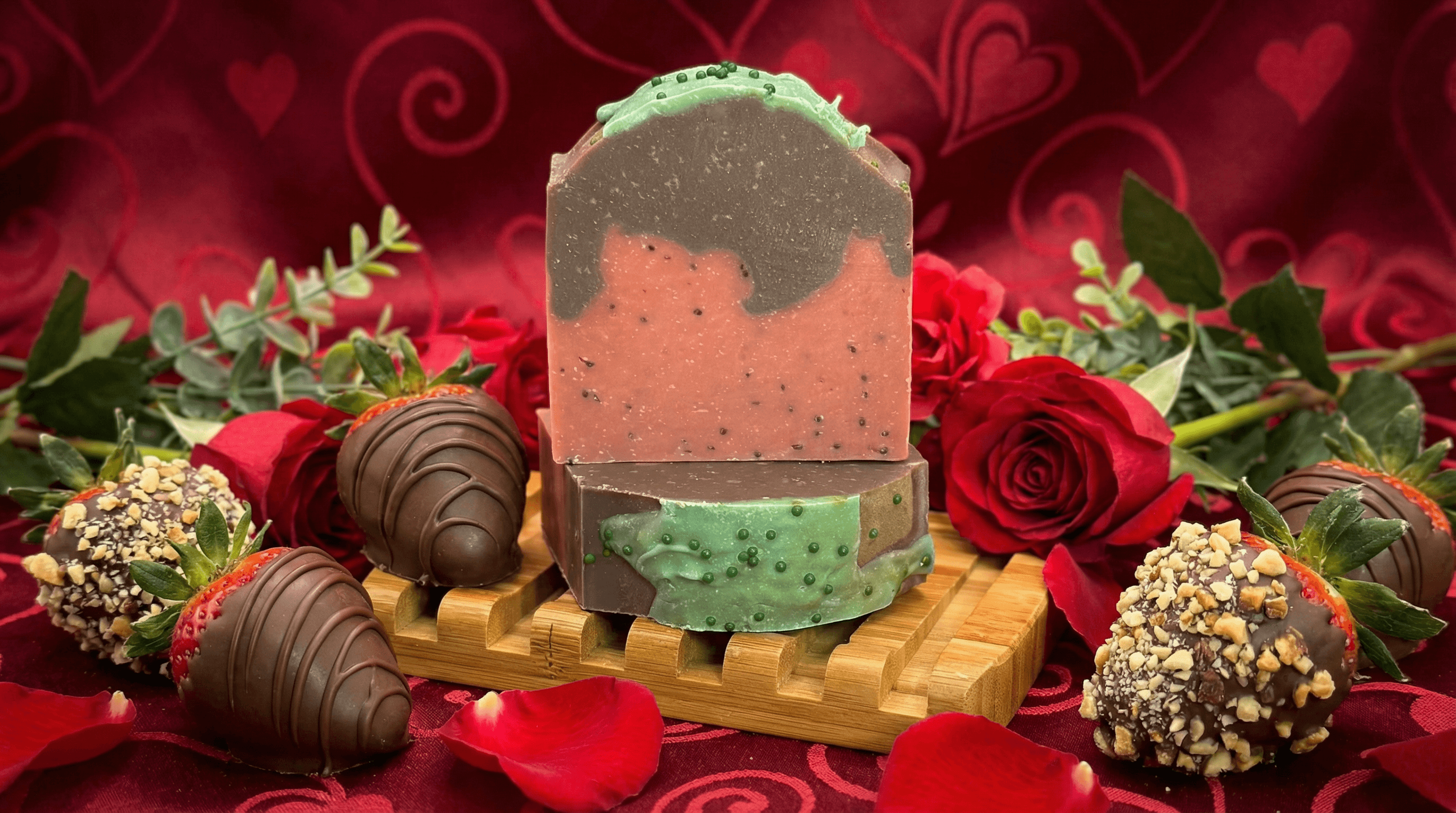 Handmade soap bar with pink speckled base, chocolate brown swirl top, and mint green frosting edge with poppy seeds. Displayed on bamboo soap dish surrounded by red roses, chocolate-covered strawberries, and rose petals.